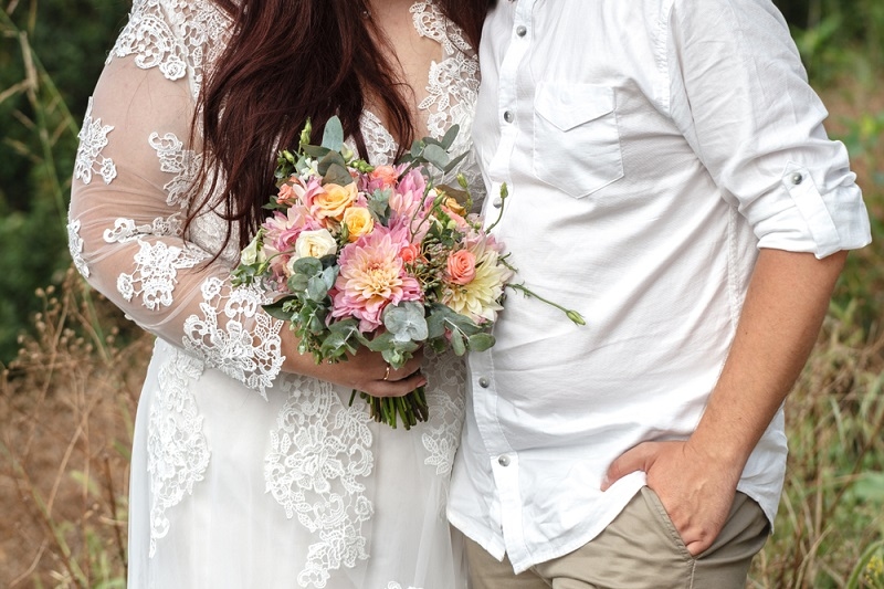 Plus size wedding couple is standing and hugging outside