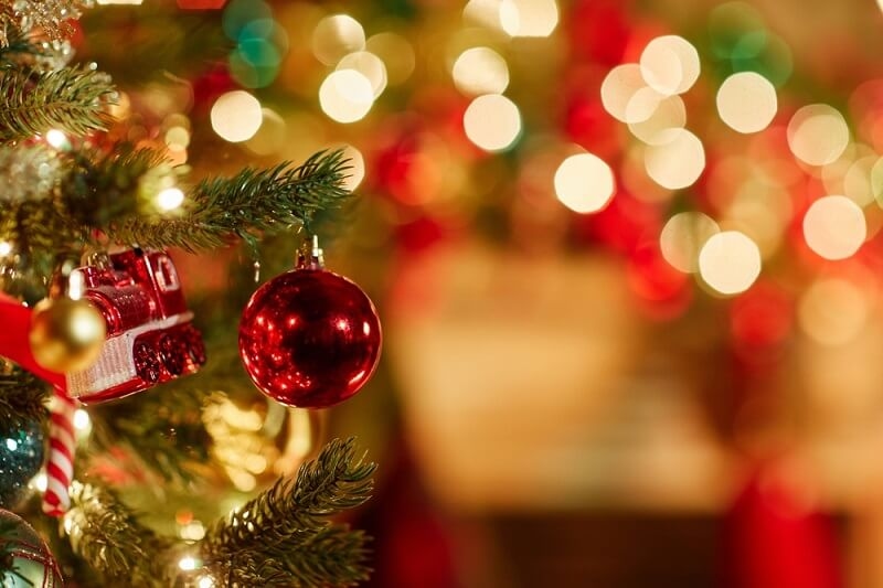 red ornament on Christmas tree with twinkling lights