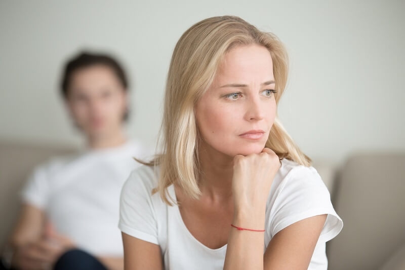 sad woman thinking over a problem, man sitting aside