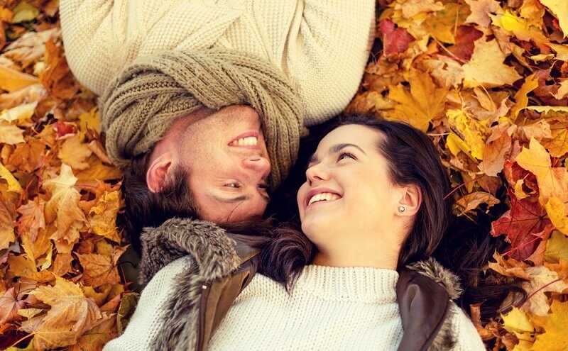 smiling couple lying in autumn park