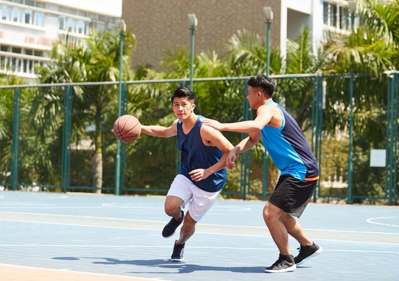 two basketball players playing one on one on outdoor court