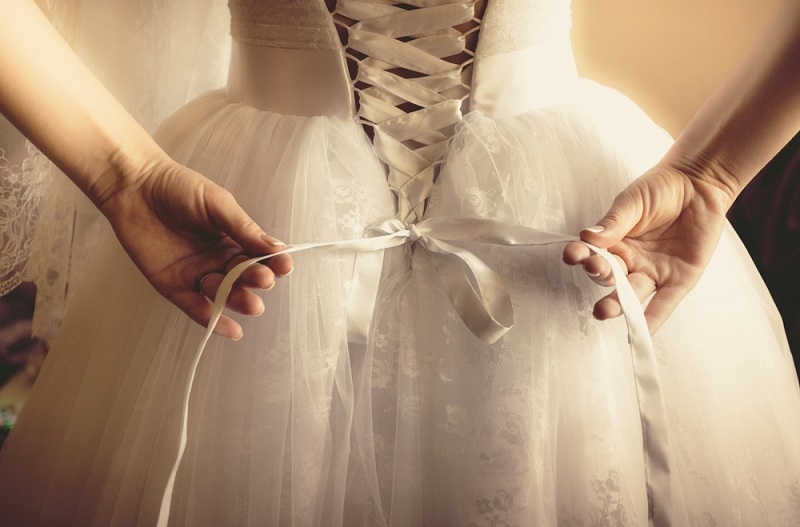 beautiful bride tying up her wedding dress