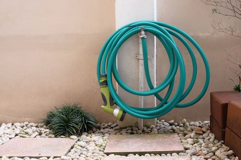 watering hose hanging on faucet in garden