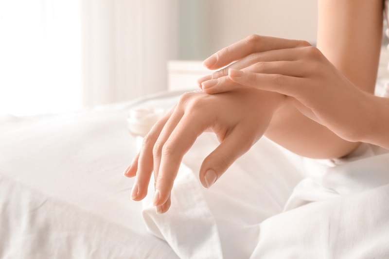 Woman applying hand cream at home