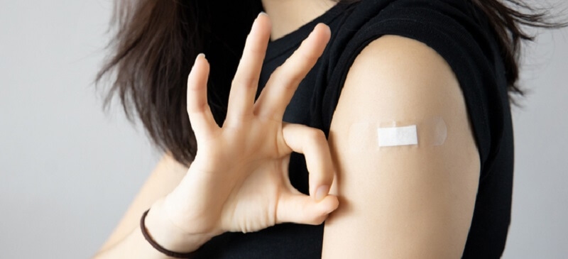 woman getting vaccinated. giving ok hand sign