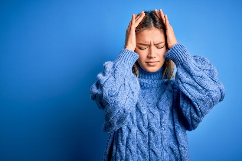 woman holding her head, suffering from migraine pain