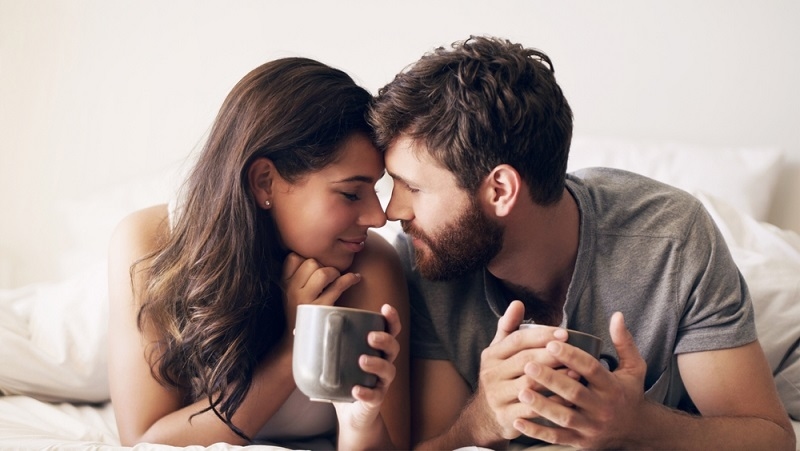 young couple having coffee together in bed