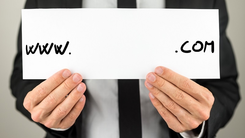 Man holding white paper with www. com written on it