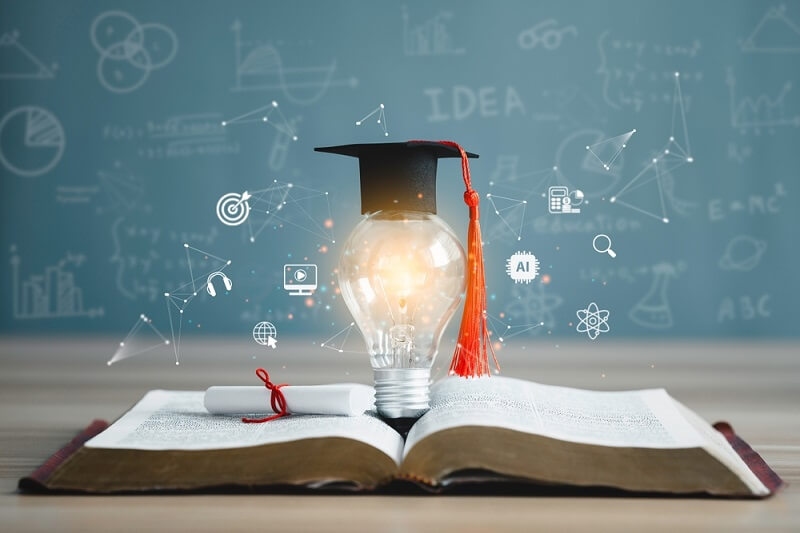 bulb with degree cap on open book showing AI in education