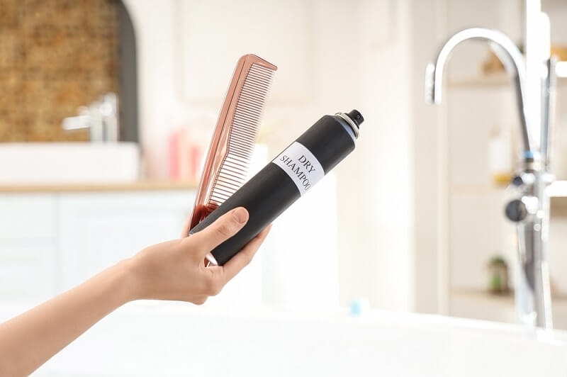 woman hand holding dry shampoo and comb