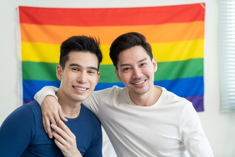 LGBTQ couple in front of flag