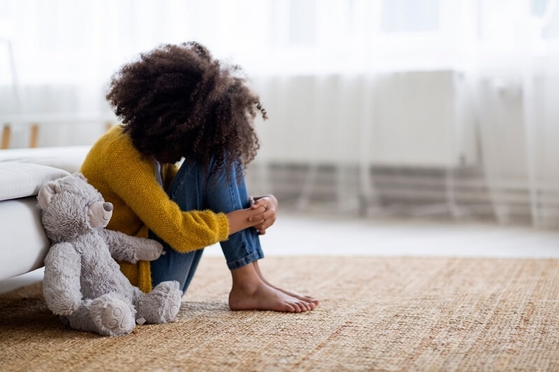 african kid sitting depressed at home near bed
