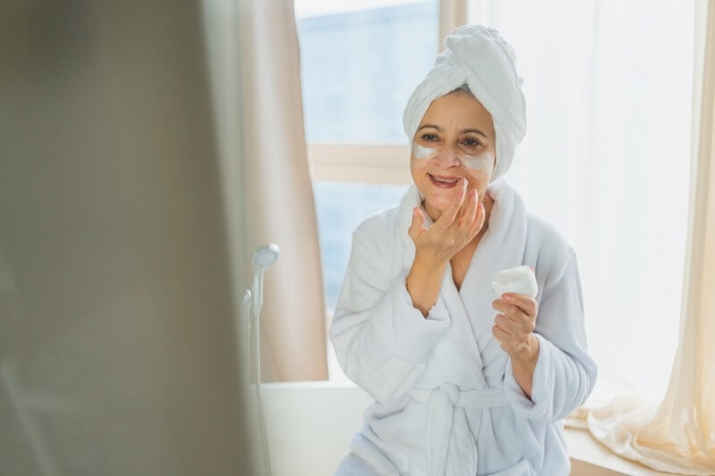 old woman applying retinol on her face