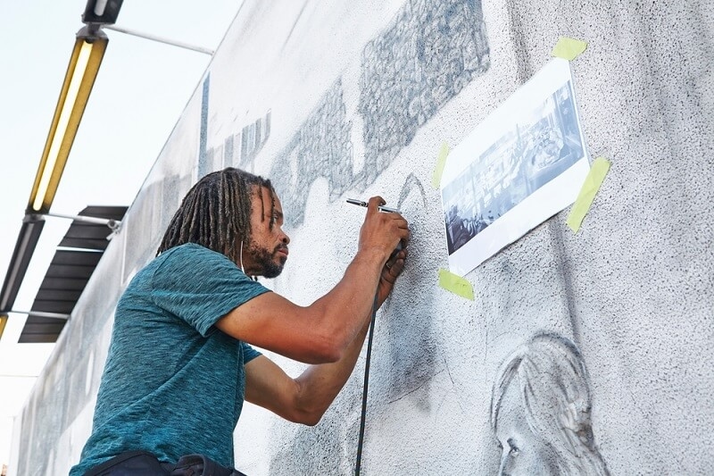 artist doing airbrushing at wall murals