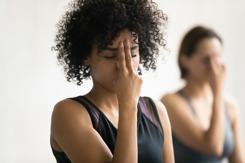 During yoga class women do Alternate Nostril powerful breathing practice energizing third eye chakra