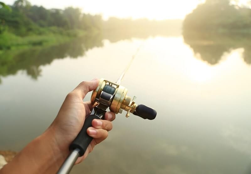 man doing fishing with bait cast reel