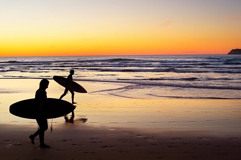 people enjoying surfing at sunset view