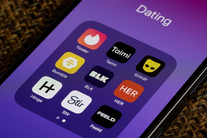 Assorted dating apps, including Tinder, Taimi, Grindr, Bumble, BLK, HER, Hinge, Stir, and Feeld, are seen on an iPhone.