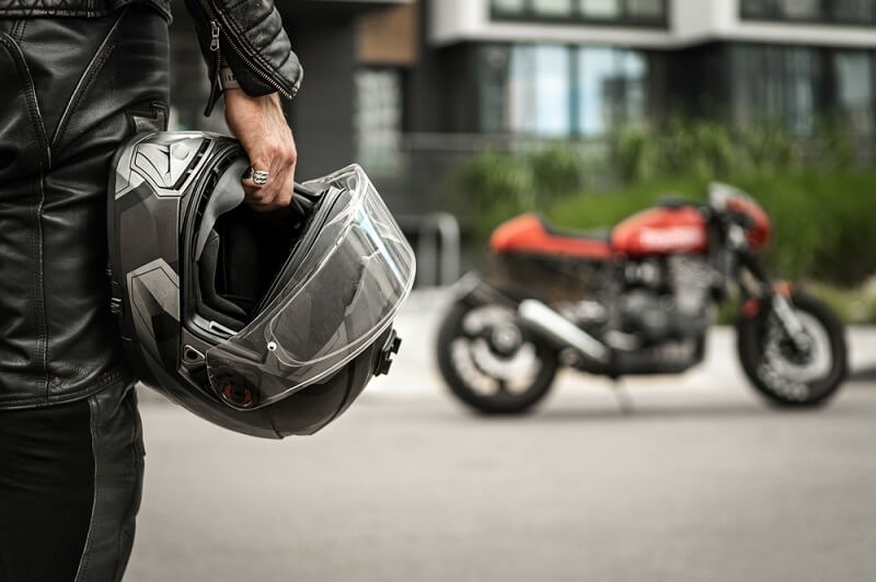 man holding helmet and going towards bike