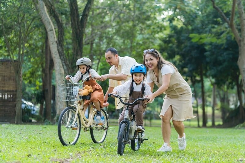 asian parents helping kids to learn riding bicycle