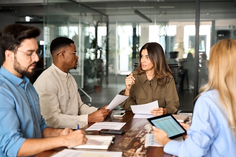 Diverse business team people having discussion at office meeting. International professional executives board group working on corporate financial strategy sitting at conference table and talking