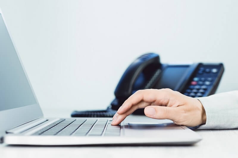 man working on laptop and phone system in background