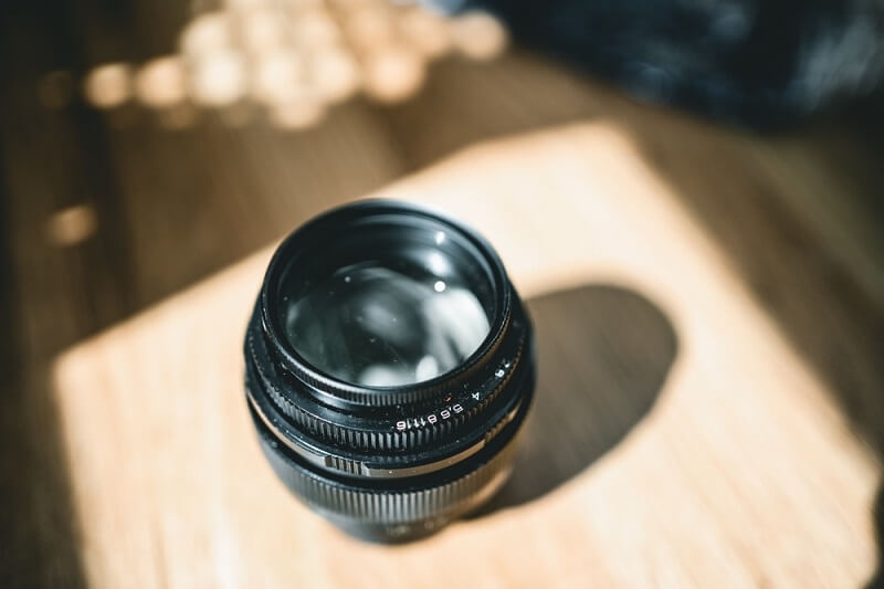 man puts camera lens in sunlight to remove fungus