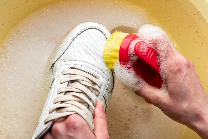 Sneakers in a wash basin with soapy water. Washing the dirty sneakers, cleaning the shoes.