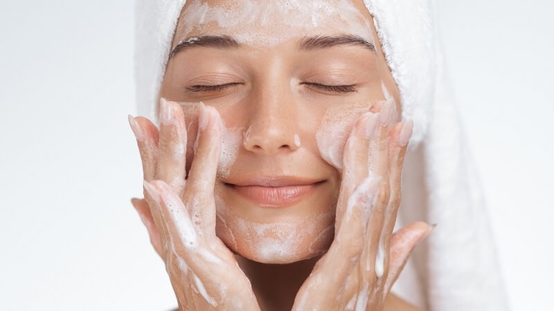 woman applying cleanser on face