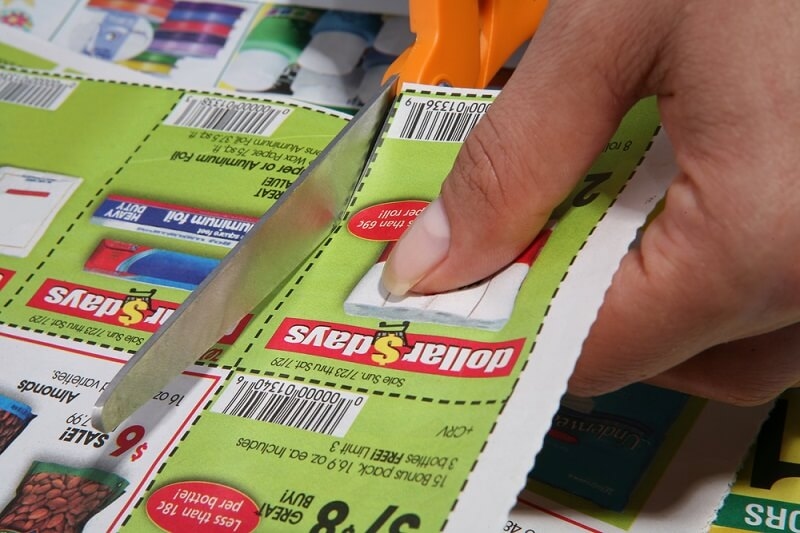 man cutting paper coupon code with scissors