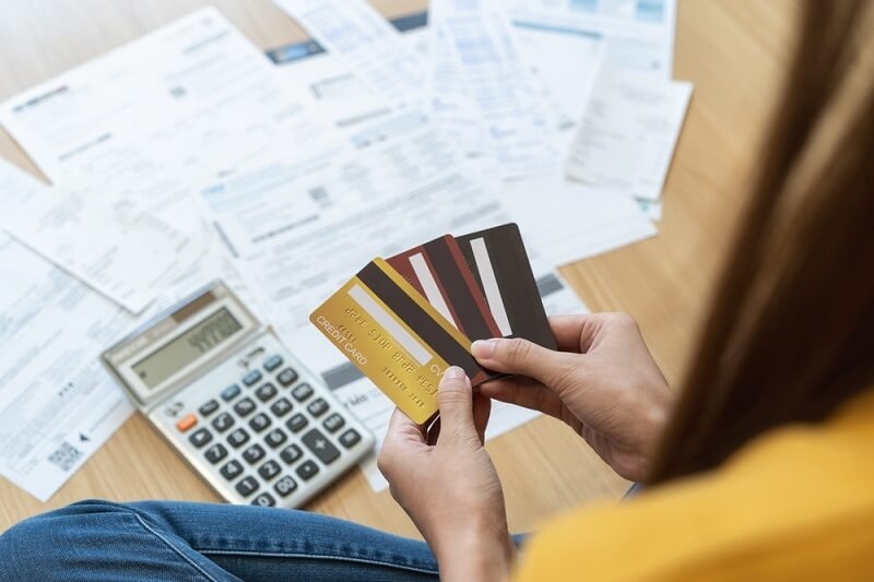woman holding credit cards and managing card debts bills