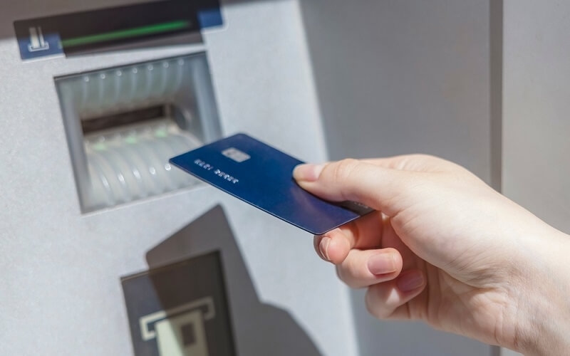 woman using debit card for withdrawling money