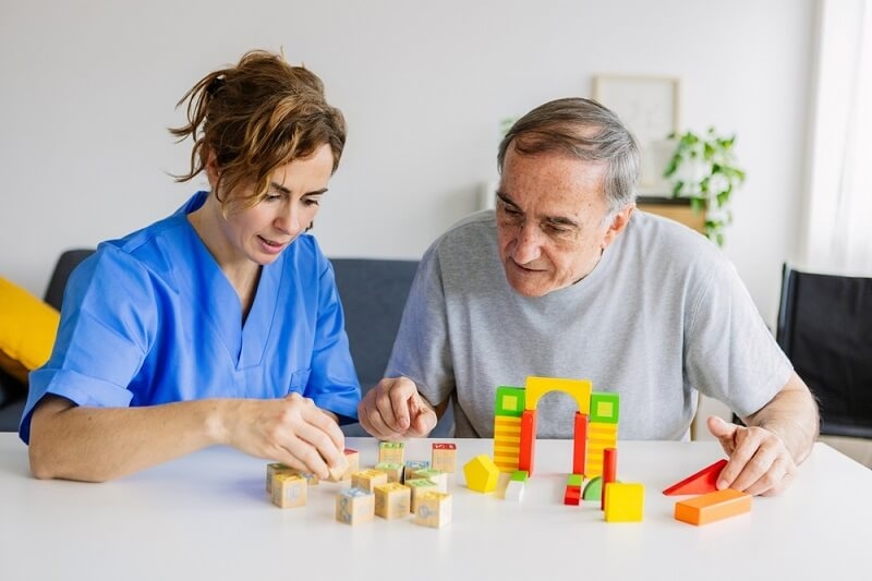 caretaker nurse engaging old man in brain enhancement activity
