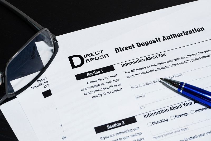Close up of corner of generic direct deposit authorization form with glasses and pen.