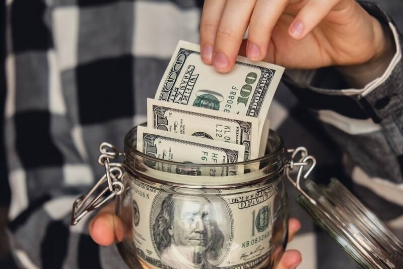 woman putting some dollars in emergency jar