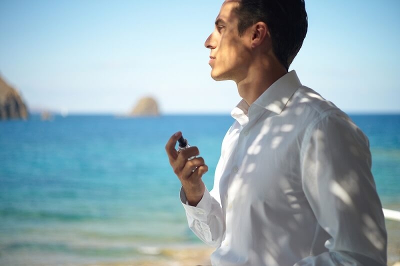 man applying eau de toilette outside