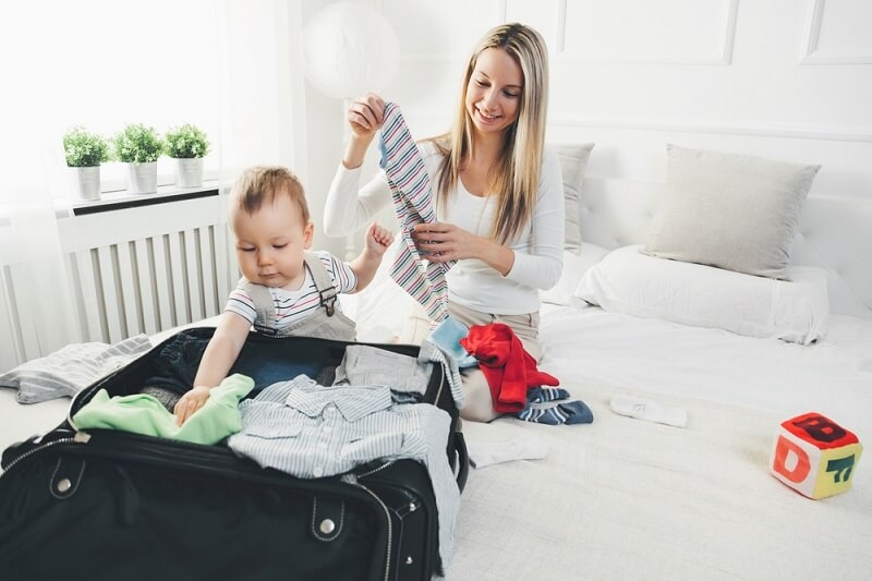 woman packaging her stuff with little baby sitting