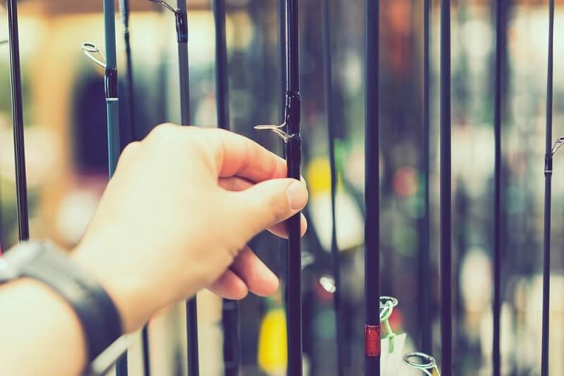 man choosing freshwater rod from rack