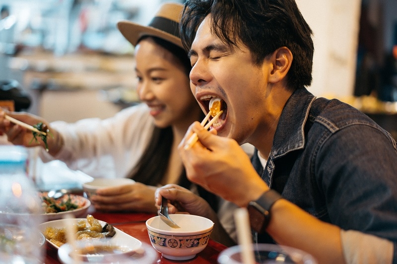 Young Asian couple traveler tourists eating Thai street food togethe