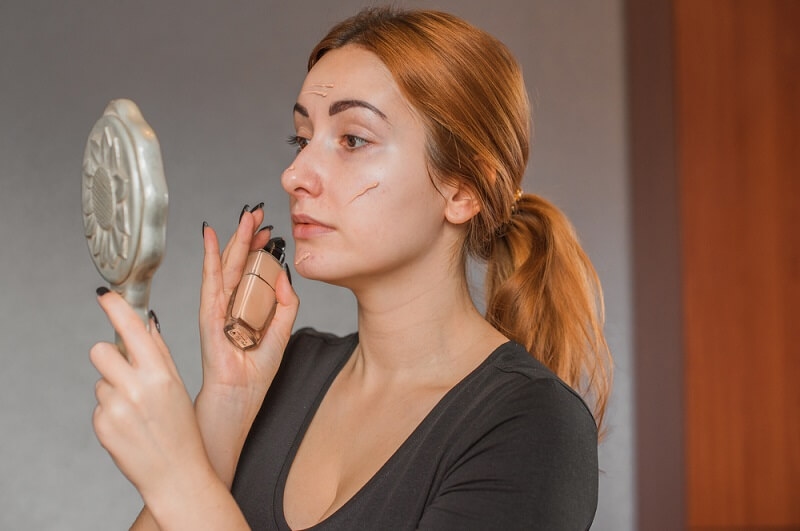 woman applying foundation on her face