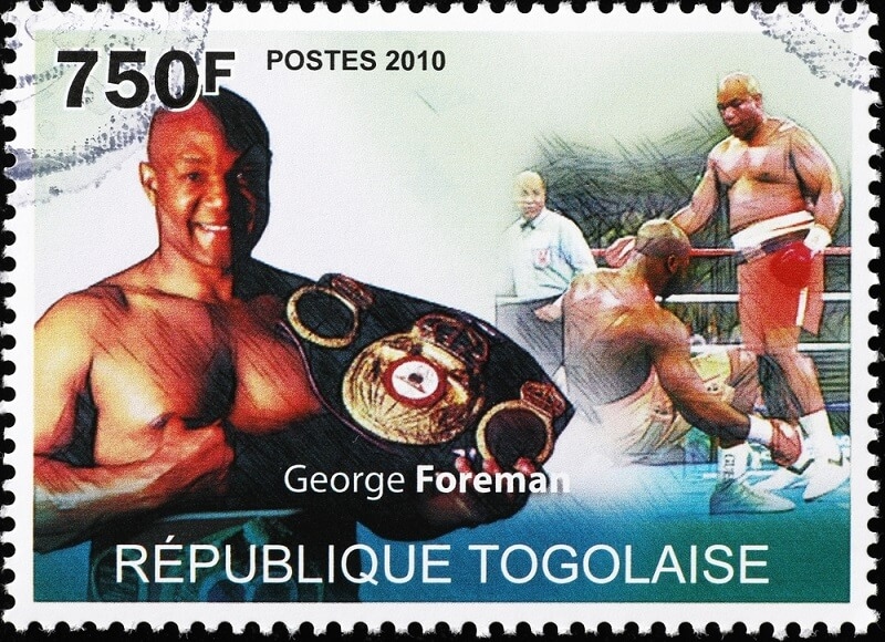 poster of george foreman with belt and match scene 