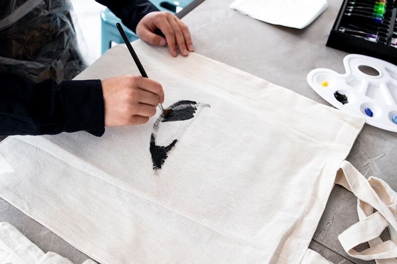 woman painting carry bag with airbrush