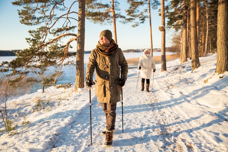 Winter sport in Finland - nordic walking. Man and Senior woman hiking in cold forest.