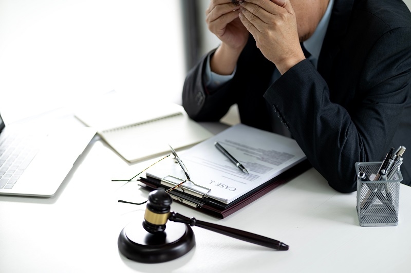 lawyer is looking through a case file thoughtfully and stressed to find a good idea to solve a legal problem in a law firm office.