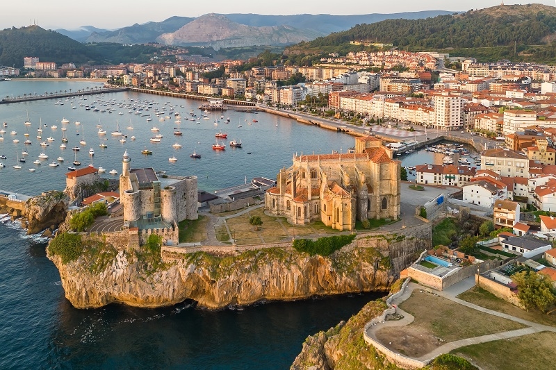 Aerial view of Castro Urdiales at sunrise, a picturesque port city on the Bay of Biscay, in Cantabria, northern Spain. Fishing boats moored in the city harbor, waterfront and historic buildings