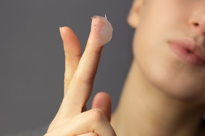 woman having petroleum jelly on her fingers