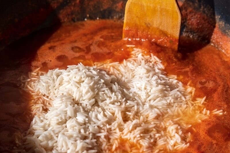 chef adding rice to base and simmering it 