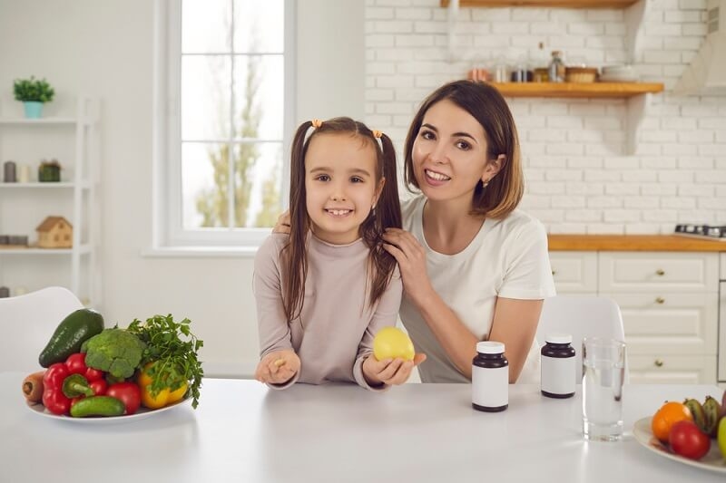 mother giving essential vitamins diet to her daughter