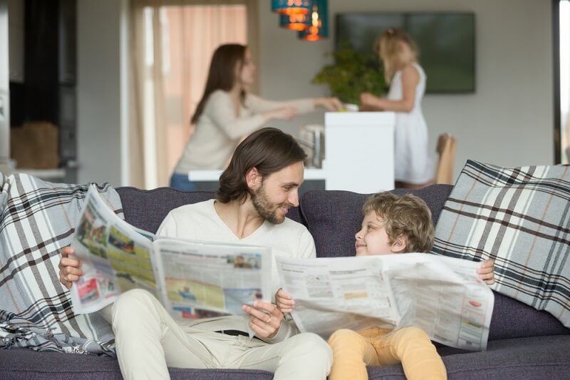little boy reading newspaper with his father