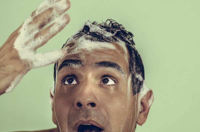 man shockingly at hair fall during shampoo